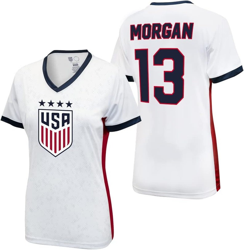May include: White football shirt with red and navy blue accents. The shirt has the USA logo on the front and the name "MORGAN" and the number "13" on the back.