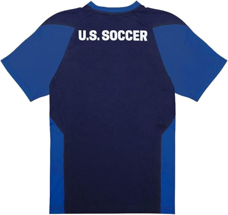 May include: A navy blue short-sleeved t-shirt with royal blue sleeves and side panels. The back of the shirt has the text "U.S. SOCCER" printed in white.