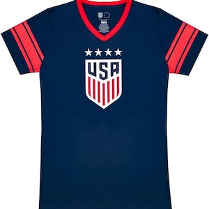 May include: A navy blue t-shirt with red and white stripes on the sleeves. The shirt has a v-neck and features a white shield with the word "USA" and five stars above it.