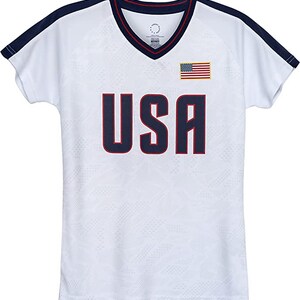 May include: White short-sleeved jersey with a navy blue and red trim. The jersey has a navy blue "USA" printed on the front with a red outline. A small American flag is printed on the right side of the chest.