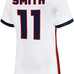 K&ouml;nnte beinhalten: Wei&szlig;es Fu&szlig;balltrikot mit marineblauem und rotem Besatz. Auf der R&uuml;ckseite des Trikots steht der Name "SMITH" und die Nummer "11" in Marineblau mit roter Umrandung.