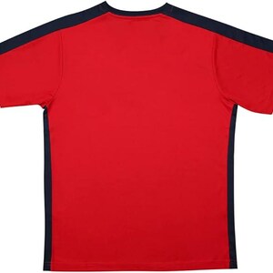 May include: A red short-sleeved t-shirt with navy blue accents on the shoulders and sides. The shirt has a crew neck and is made of a smooth, likely athletic, material. The design is simple and sporty.