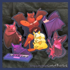 Könnte beinhalten: Eine Sammlung skurriler Fledermausaufkleber, die jeweils eine Fledermaus zeigen, die ein anderes Musikinstrument spielt, darunter Schlagzeug, Keyboard und Gitarre. Die Fledermäuse sind in verschiedenen Farben gehalten, mit einem dunklen Hintergrund.