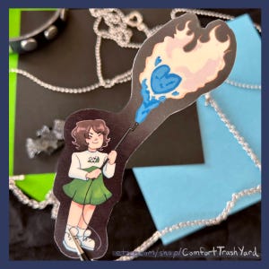 Könnte beinhalten: Ein Aufkleber mit einer Cartoonfigur, die einen Zauberstab mit einem blauen Herz- und Flammendesign hält. Die Figur trägt ein weißes Hemd, einen grünen Rock und weiße Turnschuhe. Der Aufkleber enthält den Text "etsy.com/shop/ComfortTrashYard".