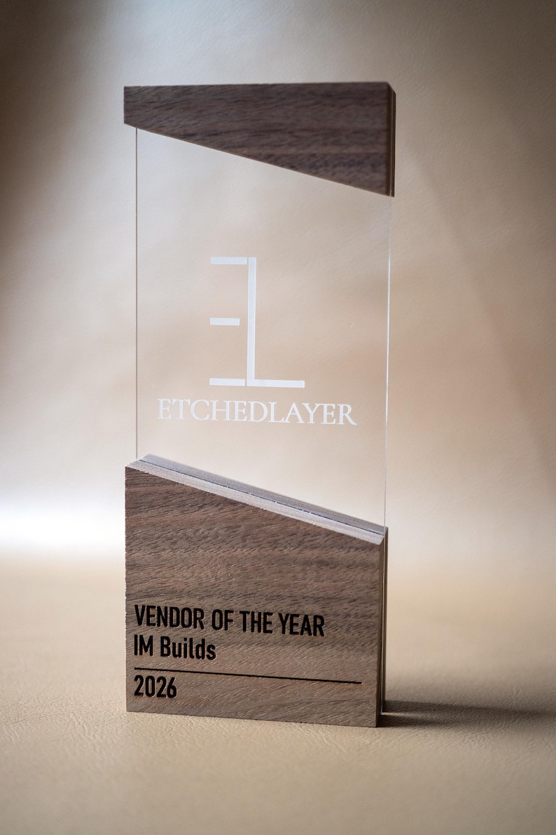 May include: A clear acrylic award with a wooden base and top. The text "ETCHEDLAYER" is etched into the acrylic. The base reads "VENDOR OF THE YEAR IM Builds 2026".