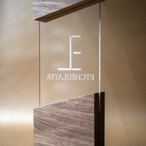 May include: A clear glass sign with the text "ELCHEDHOTEL" in white, framed by dark wood at the top and bottom. The sign has a modern, minimalist design, suitable for a hotel or business.