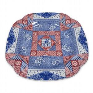 May include: A decorative ceramic plate with a unique patchwork design. The plate features a combination of blue, red, and white patterns, including floral motifs and geometric shapes. The edges have a scalloped design.