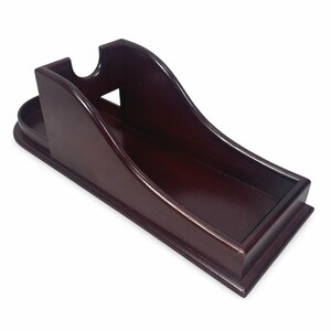 Puede incluir: Un organizador de escritorio de madera teñida de caoba oscura con un diseño curvo. Cuenta con una bandeja pequeña, una ranura y un compartimento largo y abierto. El organizador está diseñado para guardar varios artículos de escritorio.