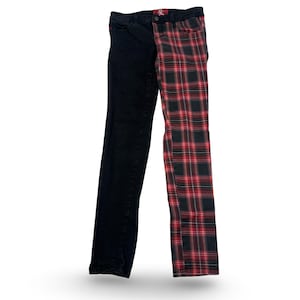 May include: Black and red plaid jeans with a unique split design. One leg is solid black, while the other features a red and black plaid pattern. The jeans have a classic five-pocket design and a button and zipper closure.