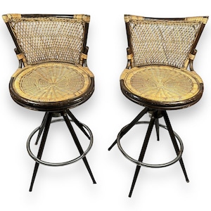 May include: Two brown wicker bar stools with black metal frames and round seats. The stools have a swivel base and adjustable height.