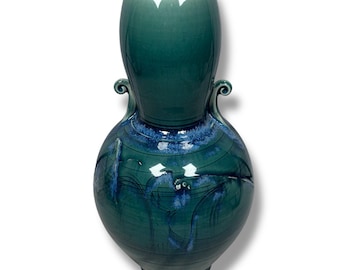 May include: A large, green ceramic vase with a bulbous body and a narrow neck. The vase has two handles and a blue and white glaze.