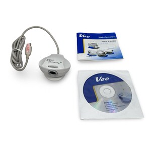 May include: A white and gray Veo Stingray webcam with a connected gray cable, a user's guide, and a CD-ROM. The user's guide is titled "Web Cameras" and the CD-ROM is labeled "Stingray".