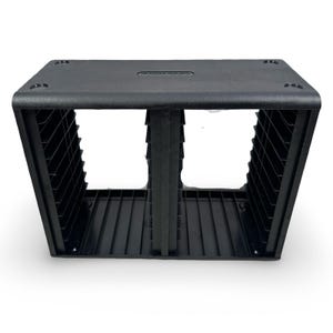 May include: A black plastic CD storage unit with a rectangular shape. The unit has two open compartments and a slotted design on the sides. The top has a small, recessed area. The unit is designed to hold CDs.