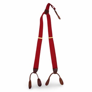 May include: Red suspenders with brown leather details and gold-colored metal accents. The suspenders have a classic design with adjustable straps and leather button attachments. A stylish accessory for formal or casual wear.