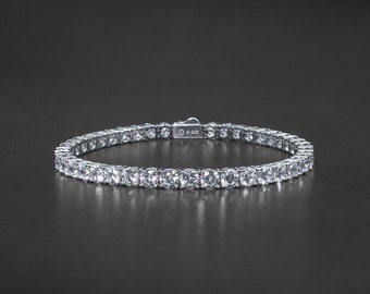 May include: A silver tennis bracelet with a row of round, clear cubic zirconia stones.
