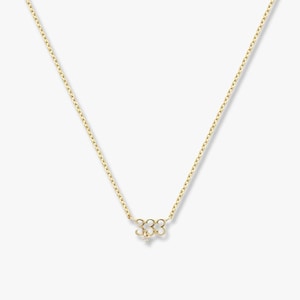 May include: A gold-coloured necklace with a fine chain and a pendant. The pendant is in the shape of the number "333" with a small, sparkling accent. The necklace is shown against a plain background.
