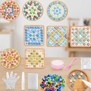 May include: A DIY mosaic craft kit featuring various circular and square wooden coasters with colorful glass tiles in star and square shapes. Includes a pink mixing bowl, a pink spoon, a white glove, a white spatula, a sponge, and loose tiles.