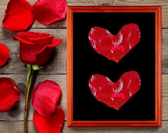 May include: A red framed artwork with two red hearts on a black background. The word "LOVE" is visible on each heart. A red rose and scattered petals are on a wooden surface.