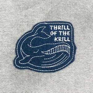May include: A blue embroidered patch with a whale design and the text "THRILL OF THE KRILL" in white.