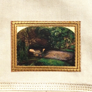 May include: Embroidered patch featuring a framed painting of a person reclining in a pond surrounded by greenery. The painting has a gold-colored frame and is set against a white fabric background.