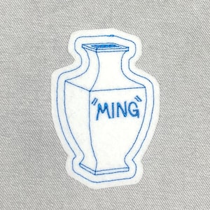 May include: Blue embroidered patch of a white vase with the word "MING" on it.