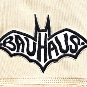 May include: Black and white embroidered patch of a bat with the word "BAUHAUS" inside.