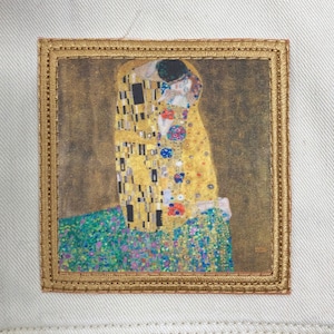 May include: A gold framed picture with a painting of two people embracing. The painting is in a mosaic style with gold, yellow, and blue colors.