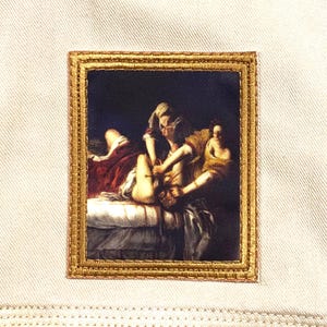May include: Embroidered patch featuring a classical painting within a gold frame. The artwork depicts figures in a dramatic scene, with rich colors and detailed brushstrokes. The patch is sewn onto a light-colored fabric.