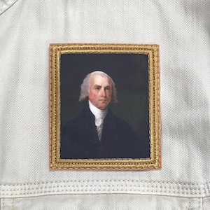 May include: A framed portrait of a man with white hair and a white collar. The portrait is set against a dark background and has a gold frame.