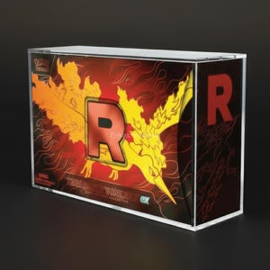 May include: A clear, rectangular display case featuring a vibrant design. The artwork showcases a fiery yellow and orange phoenix with a large red "R" and the text "TEAM ROCKET'S MOLTRES EX". The case is likely for a collectible item.