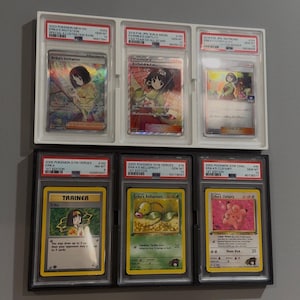 May include: A collection of six Pokémon trading cards, each encased in a protective holder. The cards feature various characters and designs, including Erika's Invitation and Erika's Bellsprout. The cards are displayed in a grid formation.