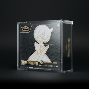 May include: A clear, rectangular box featuring a black and gold design. The box displays a white and gold illustration of a character, with the words "MEGA EVOLUTION" and "Pokémon Center ELITE TRAINER BOX" in gold lettering. The box is on a black surface.