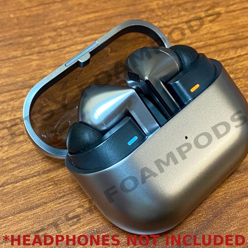 May include: A silver and black wireless headphone charging case with the word "FOAMPODS" printed on the side.