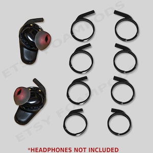 May include: Black wireless earbuds with red ear tips and black earbud rings are displayed on a light gray background. The text "*HEADPHONES NOT INCLUDED" is at the bottom of the image. The image is for replacement earbud accessories.