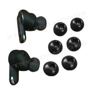 May include: Black wireless earbuds and replacement ear tips. The earbuds are black with a sleek design. Six black ear tips of varying sizes are also included, offering a comfortable fit. The image is set against a white background.