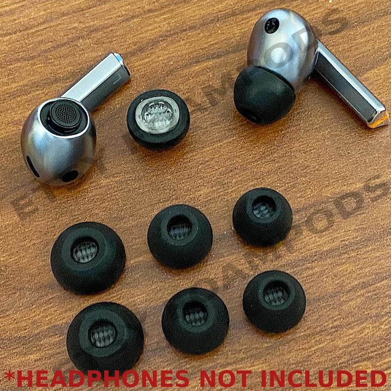 May include: A set of seven black earbud tips for headphones, including one pair of larger tips. The tips are arranged on a wooden surface.  *HEADPHONES NOT INCLUDED*