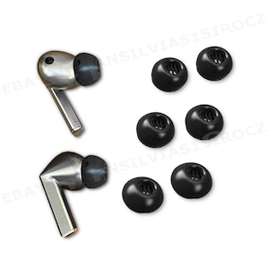 May include: A set of silver wireless earbuds with black ear tips, alongside six additional black ear tips. The earbuds have a sleek, modern design, and the ear tips are a soft, rounded shape. The items are displayed on a white background.