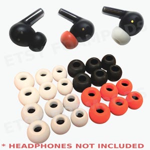 May include: A collection of replacement ear tips in various colors and sizes. The image shows black, white, and orange ear tips, along with three black earbuds with ear tips attached. The text at the bottom reads "HEADPHONES NOT INCLUDED."