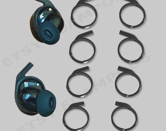 Könnte beinhalten: Zwei schwarze kabellose Ohrhörer mit Silikonaufsätzen und acht schwarze, kreisförmige Ohrbügel, die in zwei Spalten angeordnet sind. Der Text *HEADPHONES NOT INCLUDED steht in Rot unten, mit einem blassen Wasserzeichen im Hintergrund.