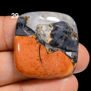 Puede incluir: Primer plano de una piedra cuadrada, pulida y multicolor con un patr&oacute;n rojo, naranja, negro, blanco y amarillo. La piedra est&aacute; etiquetada con el n&uacute;mero "29".