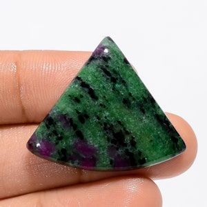 Puede incluir: Un cabujón de piedra preciosa verde, negro y morado tallado en forma triangular. La piedra preciosa tiene un patrón moteado.