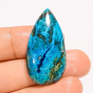 May include: A teardrop-shaped gemstone with a vibrant mix of turquoise and deep blue hues, accented by dark brown and green inclusions. The polished surface reflects light, showcasing the stone's natural patterns and textures. This gemstone is ideal for jewelry making.