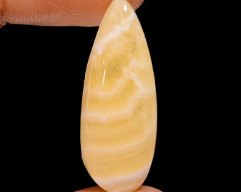 May include: A teardrop-shaped, yellow and white banded gemstone cabochon.