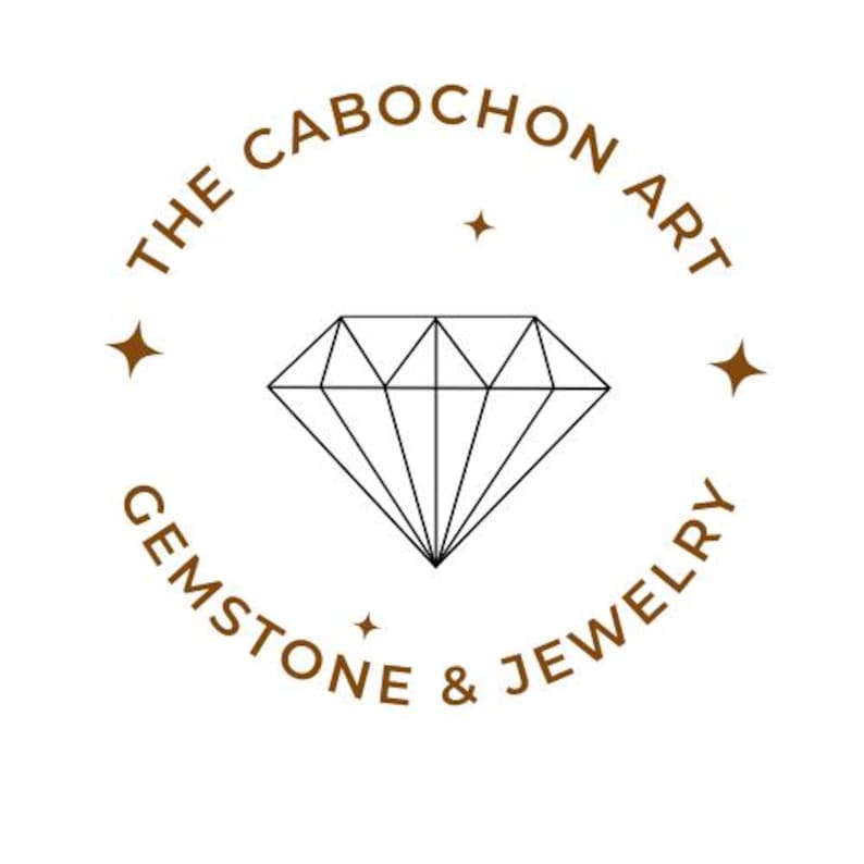 May include: Logo for The Cabochon Art Gemstone & Jewelry featuring a stylized diamond with a brown outline and the text "The Cabochon Art Gemstone & Jewelry" in a brown circle.