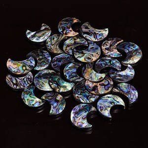 May include: A collection of iridescent abalone shell crescent moon shapes. The shells are a mix of blue, green, and purple colors.