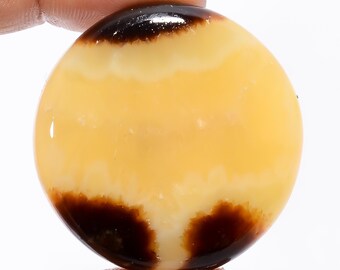 May include: A round, polished yellow and brown agate cabochon with a smooth, glossy finish.