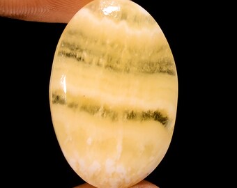 Puede incluir: Una piedra preciosa ovalada en cabujón con bandas amarillas y blancas, con una superficie lisa y pulida.