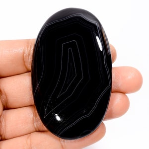 May include: Black and white agate cabochon with a swirling pattern. The cabochon is oval shaped and has a smooth, polished surface.