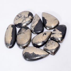 以下が含まれることがあります： 8つのパイライトカボションのセット。それぞれがユニークな形とパターンを持っています。カボションは黒と銀の組み合わせで、メタリックな輝きを放っています。