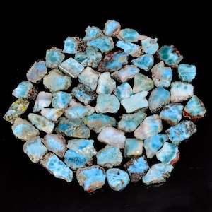 May include: A collection of blue and white gemstone chips, known as blue opal, with a variety of shapes and sizes. The chips have a natural, rough texture and are perfect for crafting or jewelry making.